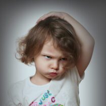 Angry kid on grey background. Closeup portrait