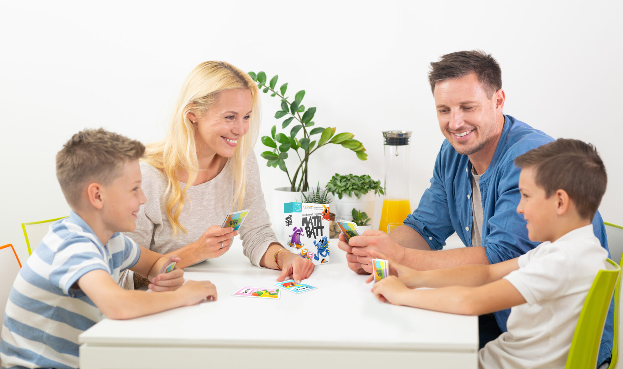 Happy young family playing card game at dining table at bright modern home.